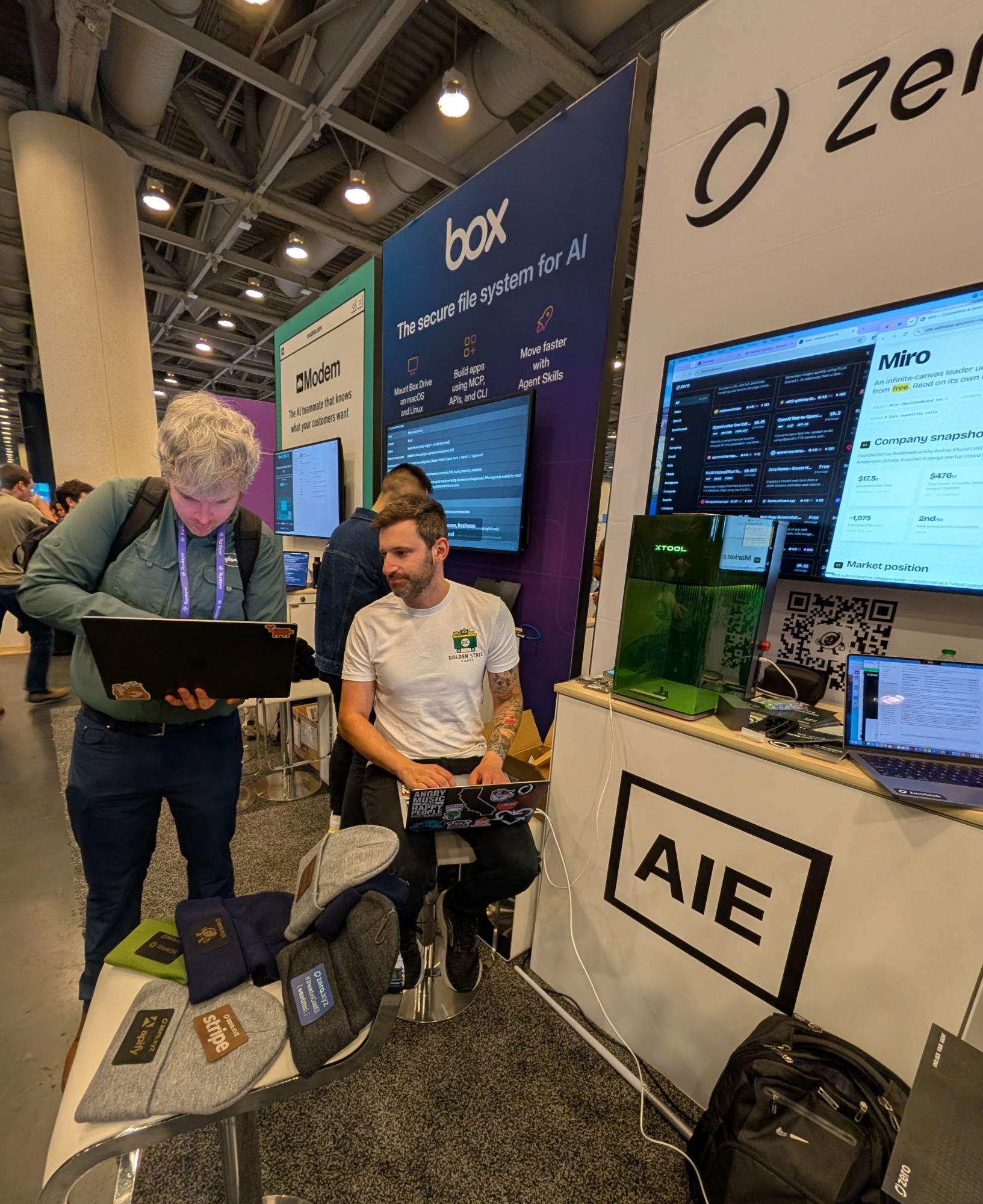 A Laser Social team member sitting at the booth, looking over a guest's laptop to personalize their design