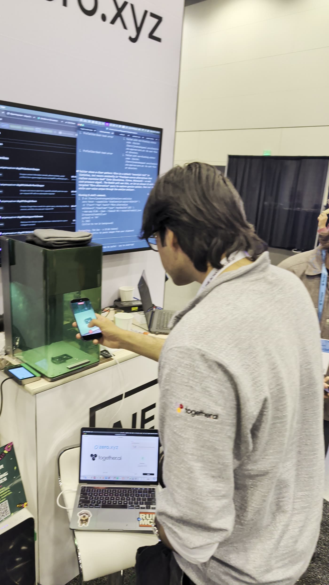 A guest filming the laser engraving an item with their phone at a conference booth