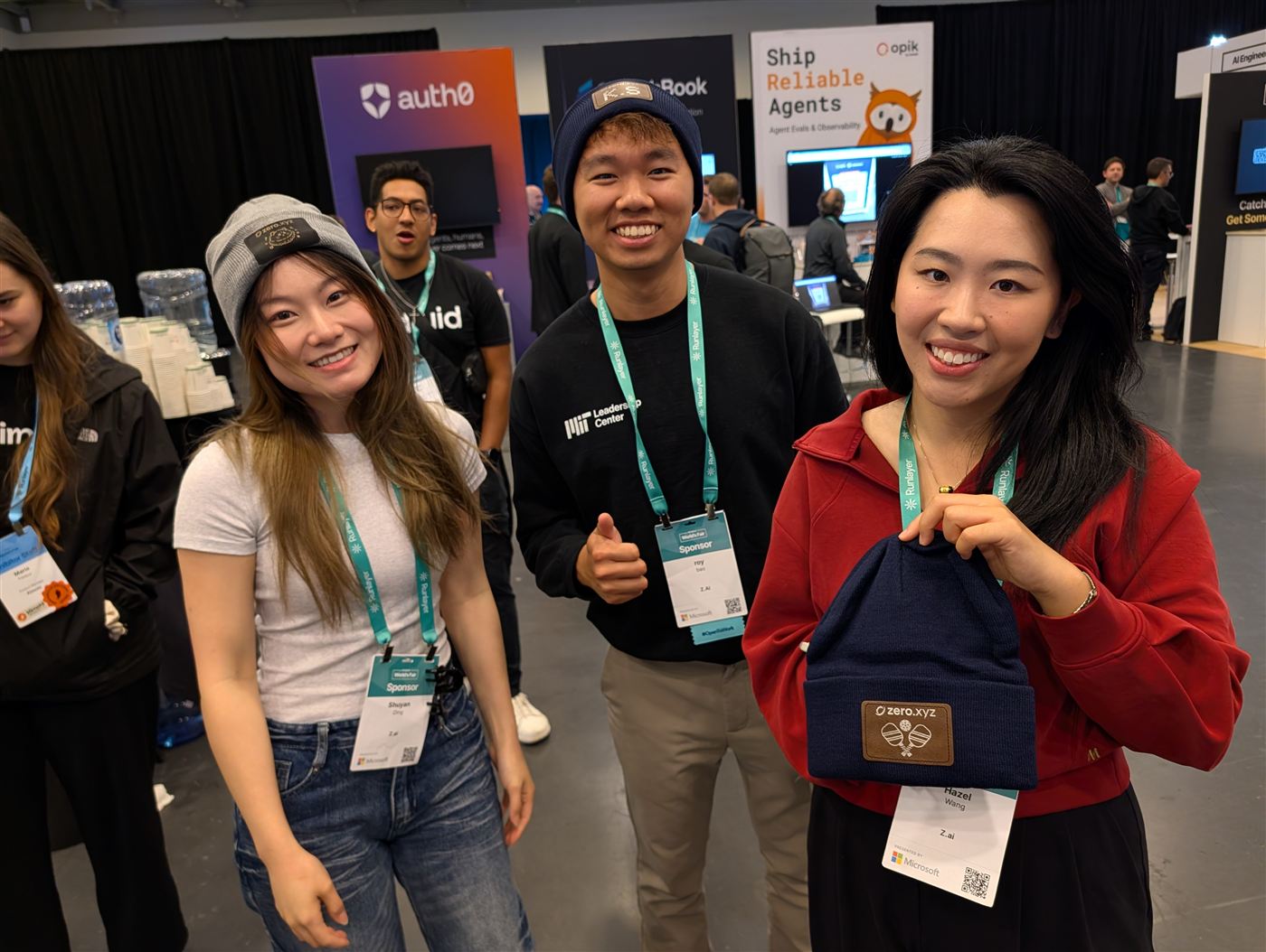 Smiling event guests wearing and holding beanies with engraved patches