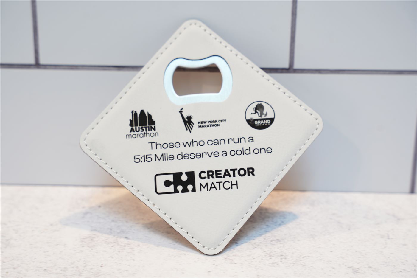 Square leatherette coaster with a built-in bottle opener, engraved with logos and a custom message